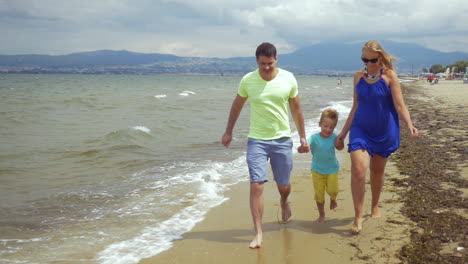 Barefoot-family-of-three-running-along-the-sea