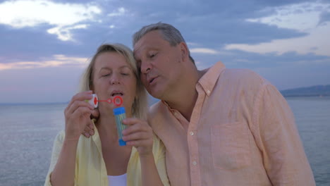 Mature-couple-blowing-bubbles-on-the-coast