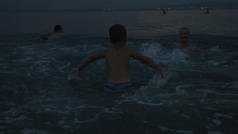 Family-with-child-bathing-in-sea-at-twilight