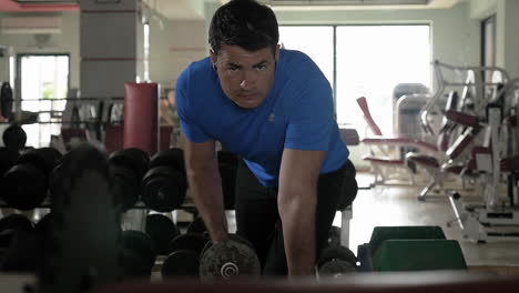 Man-exercising-with-dumbbell-in-the-gym