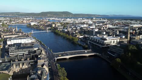 aerial-drone-footage-of-pedestrian-bridges-and-the-old-town-along-Ness-river-in-Inverness,-Scotland-in-the-Highlands