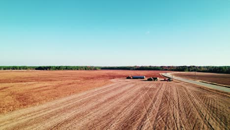 Drone-view-of-farm-machinery-during-harvest-in-a-vast,-golden-crop-field