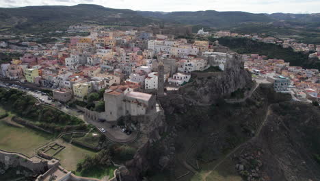 Stadt-Castelsardo,-Sardinien:-Luftaufnahme-Im-Kreis-über-Der-Farbenfrohen-Stadt-Und-Ihrem-Historischen-Turm-Auf-Der-Insel-Sardinien