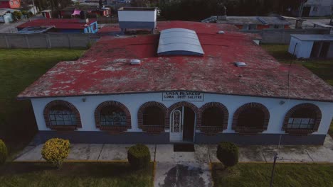 Aerial-footage-of-a-historical-health-center-building-in-Ecatepec-de-Morelos,-Mexico,-showcasing-its-antique-style-door-and-windows