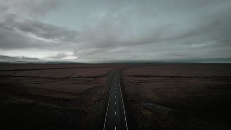 Cinematic-aerial-empty-road-in-mossy-volcanic-stone-nature,-epic-moody-dark-landscape-scenery-iceland