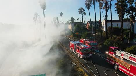 Aerial-view-of-firetrucks-near-a-smoking-I-10-in-Arlington-Heights,-Los-Angeles