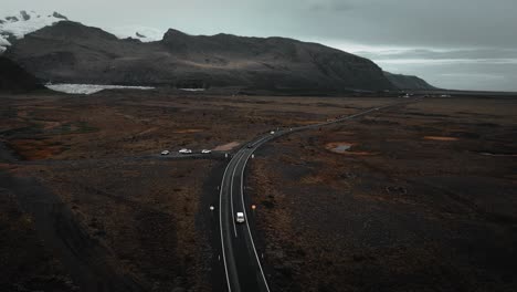 aerial-tracking-jeep-driving-on-road,-rocky-volcanic-mountain-nature,-epic-moody-dark-landscape-scenery-iceland