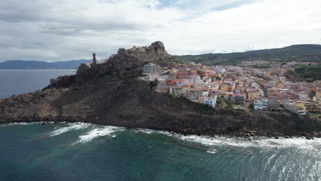 city-of-Castelsardo,-Certeña:-aerial-view-in-orbit-over-this-impressive-city-of-colorful-houses-and-its-historic-tower