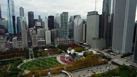Aerial-view-tilting-over-the-Jay-Pritzker-Pavilion,-fall-evening-in-Chicago,-USA