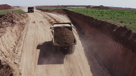 A-large-truck-loaded-with-sand-is-heading-towards-the-construction-site,-aerial-shots-of-the-truck-alongside-the-construction-site-and-materials