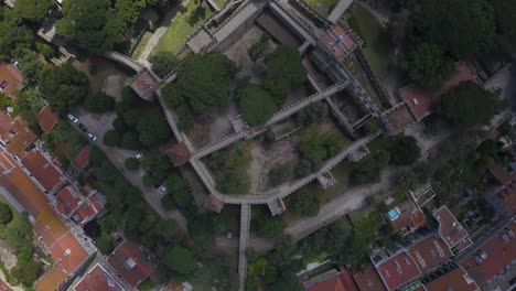 Top-down-rotating-view-of-Sao-Jorge-castle-walls-under-cloud-shadow