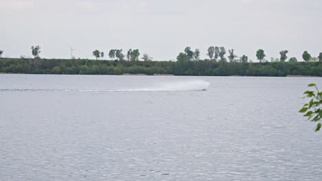 A-Speedboat-Maneuvering-Through-the-Lake,-Creating-a-Splash-of-White-Water-in-its-Wake---Wide-Shot