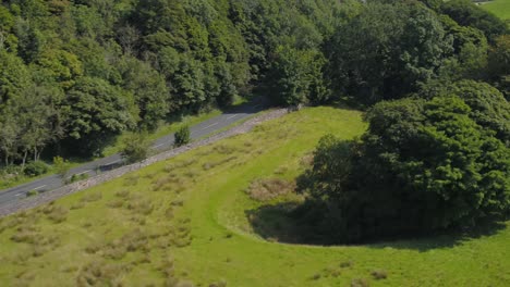 Wunderschöne-Drohnenbewegung-Vom-Fuß-Eines-Mit-Bäumen-Bedeckten-Kalksteinfelsens,-Die-Aufsteigt-Und-Schwenkt-Und-Täler,-Hügel,-Ackerland,-Felder,-Trockenmauern-Und-Die-Ländliche-Landschaft-Von-Yorkshire-Freigibt