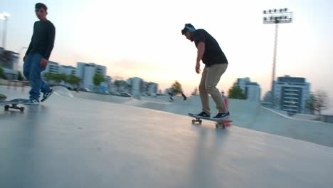 Wide-shot-of-a-young-man-performing-skateboard-tricks-at-sunset-in-tourist-spot-skatepark,-Skateboarder-jumping
