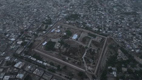 Aerial-drone-tilt-down-shot-over-an-old-historical-fortress-in-an-old-city-of-Umerkot,-Tharparkar,-Pakistan-during-evening-time