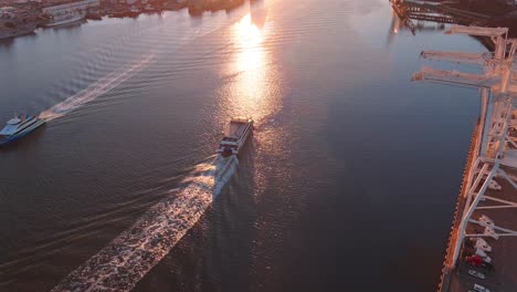 Ferry-in-the-Port-of-Oakland-estuary-going-to-San-Francisco---sunset-aerial