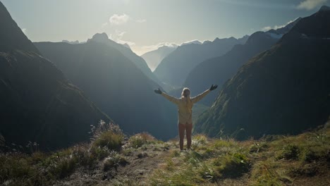 Joyful-woman-putting-hands-in-the-air-while-looking-at-blissful-mountain-view