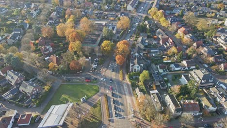 Aerial-of-cars-driving-over-a-busy-main-road-in-a-beautiful-small-town-on-a-sunny-autumn-day