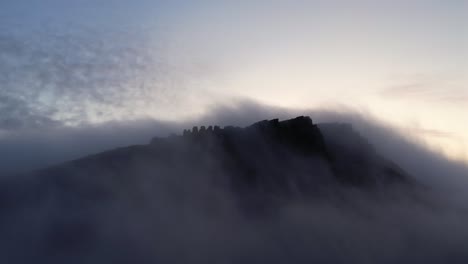 Silhouette-of-rocky-cliffs-above-clouds-and-fog