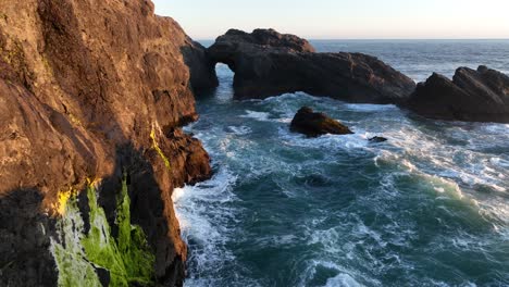 Oregons-Küste-Zerklüftete-Küste,-Während-Einige-Mächtige-Wellen-Gegen-Die-Felswände-Krachen-Und-Einen-Bogen-Im-Ozean-überfliegen
