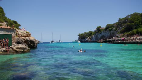 Mallorca:-Strandseitenansicht-Des-Resorts-In-Cala-Liombards-Auf-Der-Insel-Mallorca,-Spanien,-Europa-|-Drei-Frauen-Auf-Einer-Klippe
