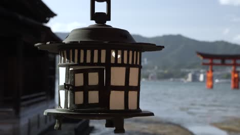 Sanft-Wiegende-Hängelaterne-Am-Itsukushima-Schrein-Mit-Bokeh-Hintergrundansicht-Des-Großen-Schwebenden-Torii-Tors