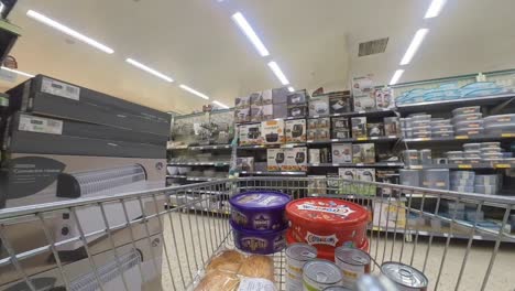 POV-Supermarkt-Einkaufswagen,-Der-Den-Gang-Mit-Haushaltslebensmitteln-Entlang-Läuft