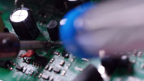 Electronic-printed-circuit-board-or-PCB-with-transistors-and-capacitors-under-repair-using-soldering-iron-and-lead