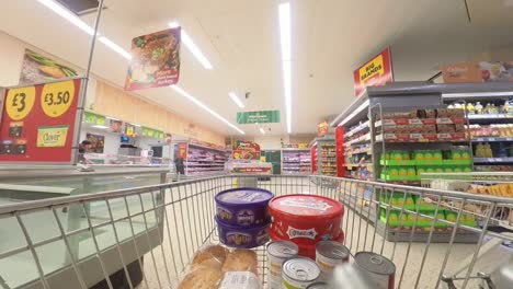 POV-supermarket-shopping-cart-walking-down-chilled-grocery-products-aisle
