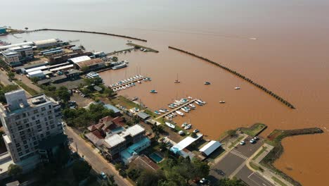 Aerial-view-showcasing-a-marina-in-the-city-of-Posadas,-Argentina,-with-the-brown-waters-of-the-Paraná-River-in-the-backdrop
