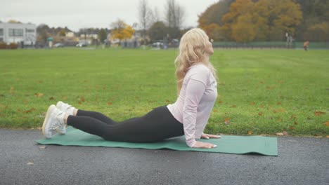 Woman-performs-Cobra-yoga-pose--in-park