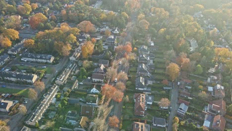 Luftaufnahmen-Von-Autos,-Die-Im-Herbst-über-Eine-Lange-Straße-Durch-Eine-Wunderschöne-Ländliche-Stadt-Fahren