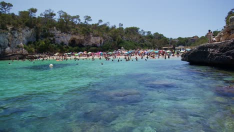 Mallorca:-Strandseitenansicht-Des-Resorts-In-Cala-Liombards-Auf-Der-Insel-Mallorca,-Spanien,-Europa-|-Überfüllter-Strand-Zum-Schwimmen