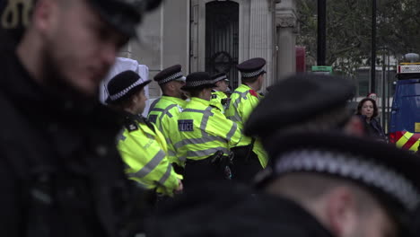 Metropolitan-police-officers-stand-guard-at-a-public-order-event-as-officers-in-black-uniforms-have-a-discussion-in-the-foreground