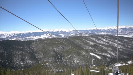 Viewing-snow-capped-mountains-on-a-cloudless-day-from-a-ski-lift,-handheld