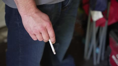 Close-up-of-a-caucasian-male-hand-holding-a-cigarette-as-it-burns