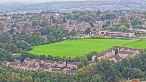 Drone-descends-below-grassy-field-surrounded-by-suburban-homes-in-Huddersfield-England