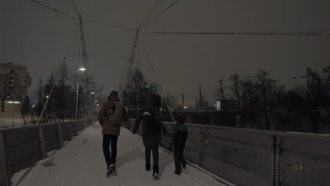 Parents-with-child-holding-hands-and-walking-in-evening-winter-city