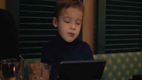 Boy-in-cafe-eating-ice-cream-and-watching-digital-tablet