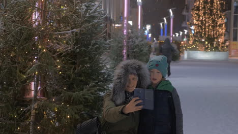 Mom-and-kid-making-winter-selfie-in-the-street-with-Christmas-illumination