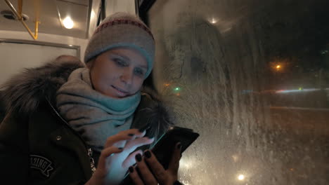 Frau-Benutzt-Mobiltelefon-Während-Der-Busfahrt-Am-Winterabend