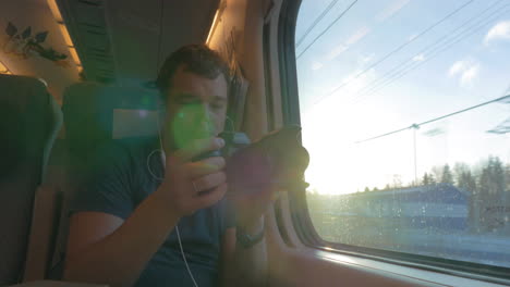 Man-in-train-shooting-footage-and-looking-out-the-window