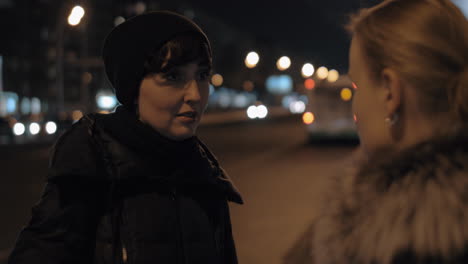 Two-women-talking-outside-in-night-city