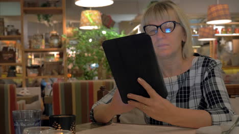 Senior-woman-browsing-on-touch-pad-in-cafe
