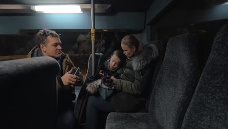 Mom-dad-and-son-traveling-bus-in-the-evening-and-using-cellphones