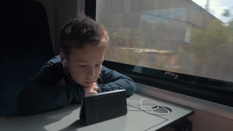 Kid-with-earphones-watching-cartoon-on-cell-in-train