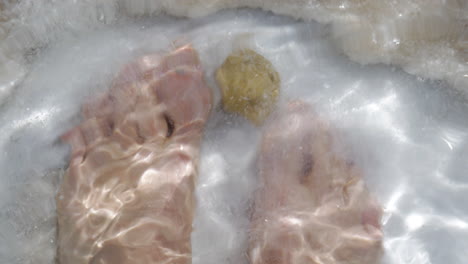 Man-feet-in-pure-salt-water-of-Dead-Sea-Israel