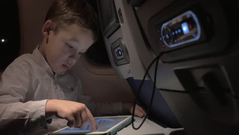 Kid-traveling-by-air-and-passing-time-with-pad-chess-game