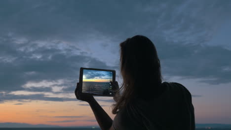 Woman-with-pad-making-photos-of-sea-and-sky-in-the-dusk