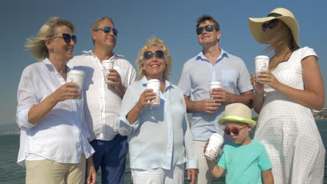 Big-family-drinking-sea-from-paper-cups-by-the-sea